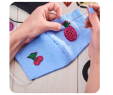 Person sewing custom patch onto fabric for long-lasting attachment — durable embroidered sew-on patch by Embrolab.