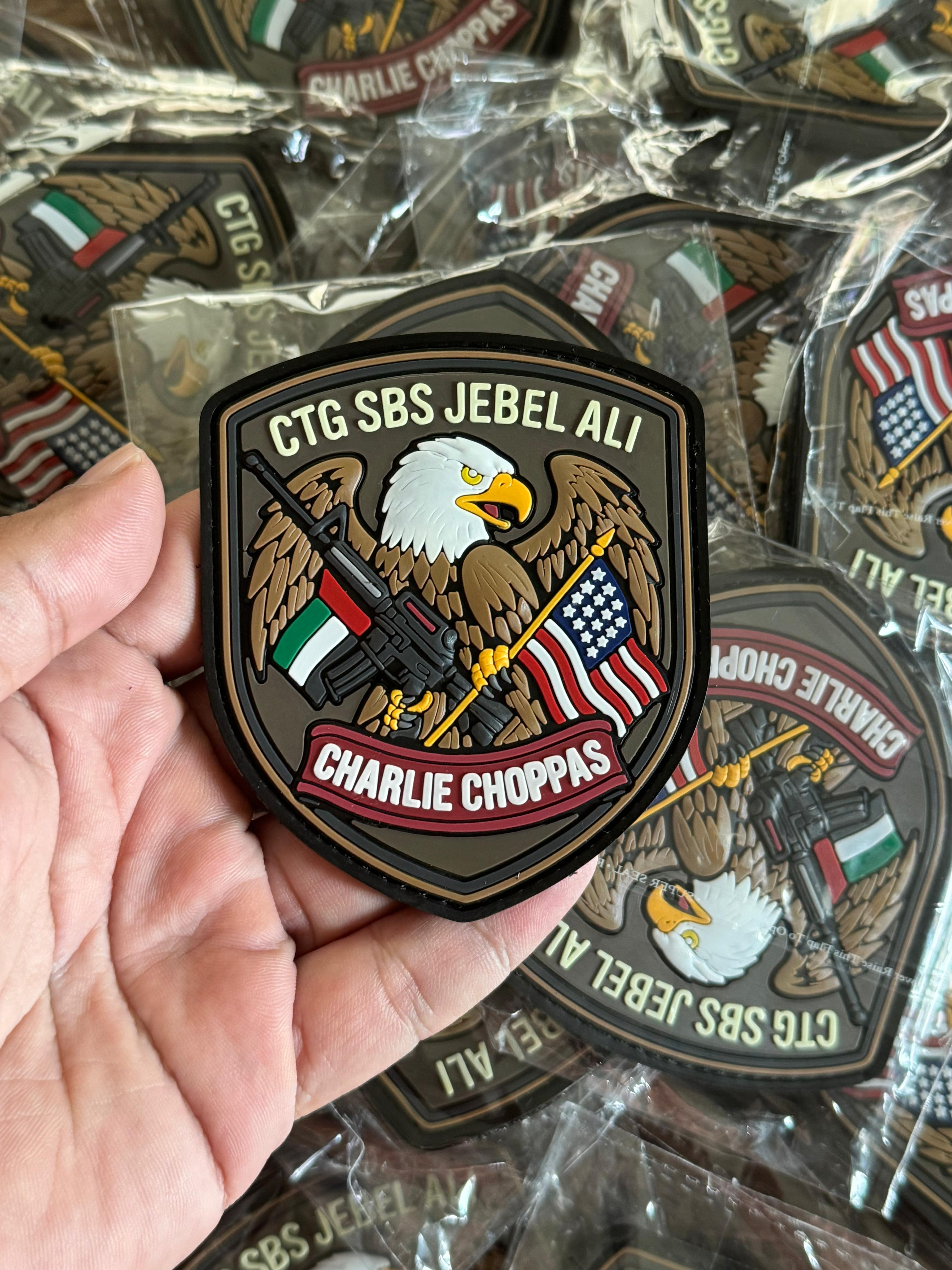 Custom PVC patch with eagle holding rifles and UAE/US flags, durable rubber patch for military uniforms and tactical use.